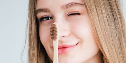 a girl holding a bamboo toothbrush