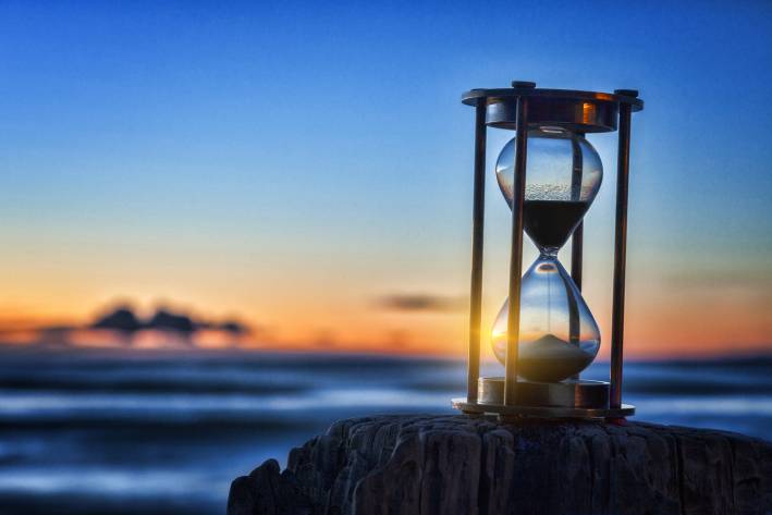 Lament sunset shining through an hourglass on the beach