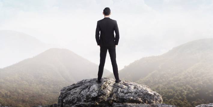 Don't Sit Down on the Job Man in suit stands looking out at the world