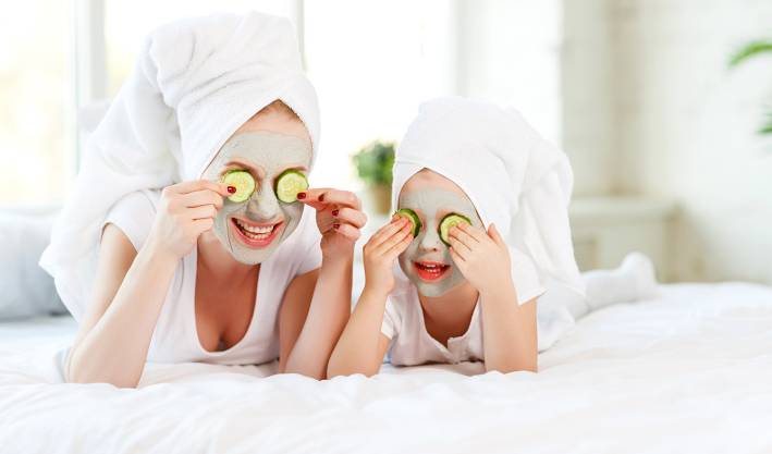 Hydrating Facial Masks Mother and child with natural face masks on, covering eyes with cucumber slices.