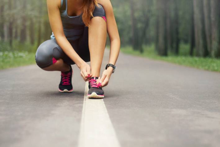 Fitness Matters for Brain Health A woman tying her shoe in preparation for a run.