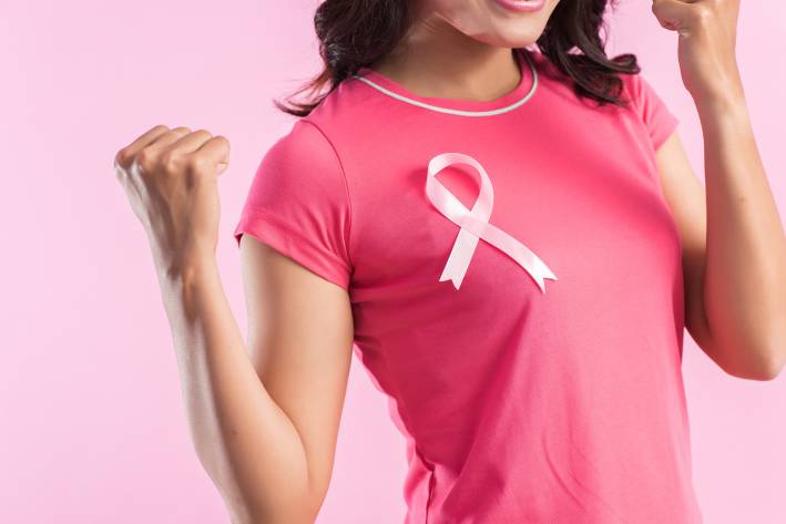 Food & Supplements for Breast Cancer Prevention A woman wearing a breast cancer ribbon and flexing her muscles