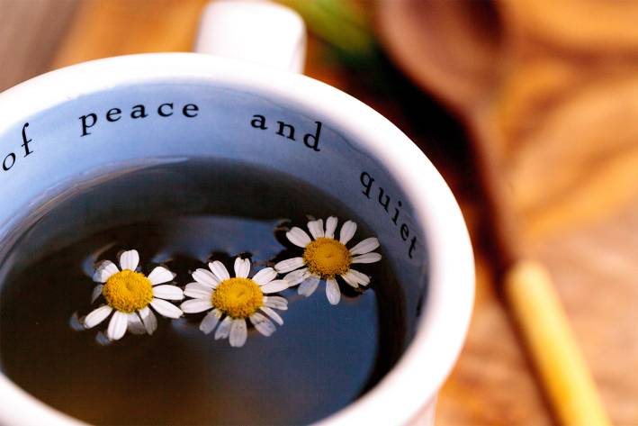 Natural Ways to Sleep Better A cup of chamomile tea. The mug says "peace and quiet."
