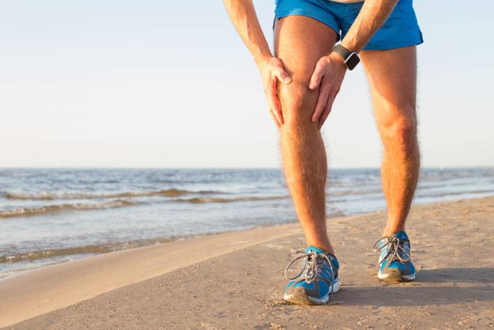 Arthritis Rx A man with an aching knee while running on the beach
