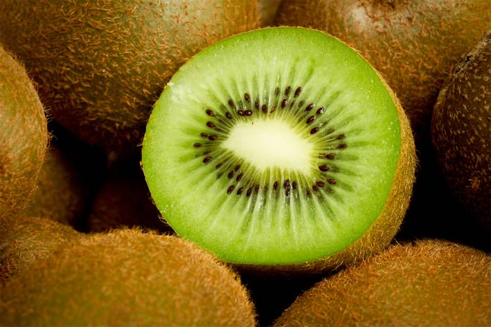 Kiwi: The Most Nutritious Fruit a sliced kiwi surrounded by whole kiwifruit