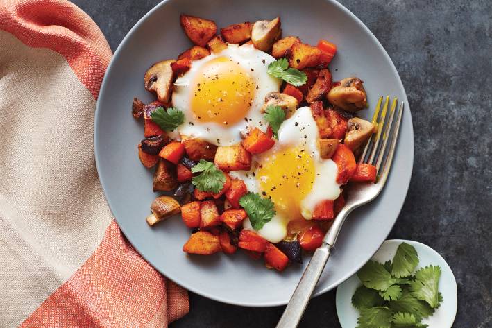 Veggie Hash with Eggs A bowl of vegetable hash with eggs roasted on top