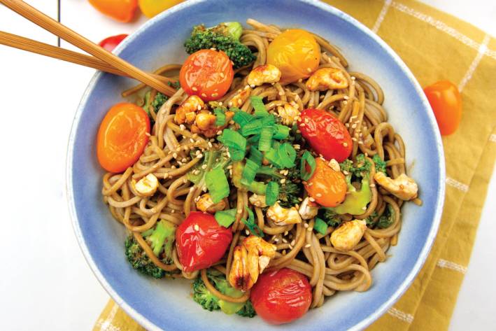 Soba with Veggies, Maple Cashews & Miso Sauce a bowl of noodles with cherry tomatoes and candied cashews