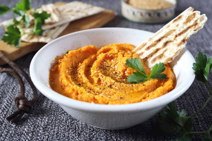 Roasted Carrot Hummus a bowl of carrot dip ready for a party