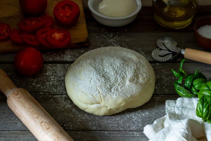 Easy Pizza Crust a ball of floured pizza dough and other ingredients