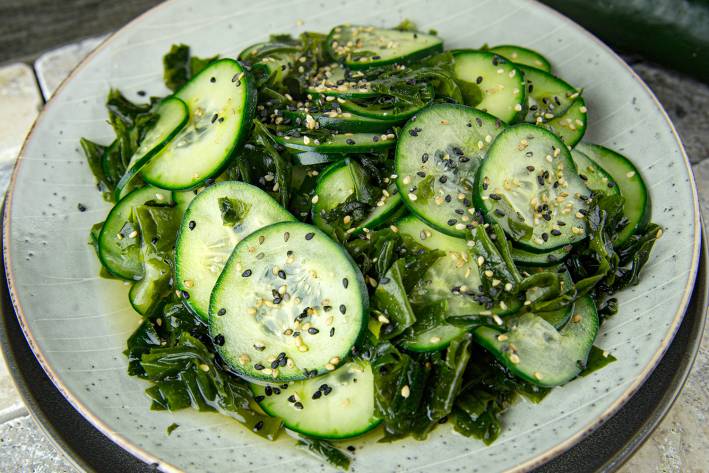 Cucumber Wakame Salad a plate of cucumber with oil, vinegar, wakame flakes, and sesame