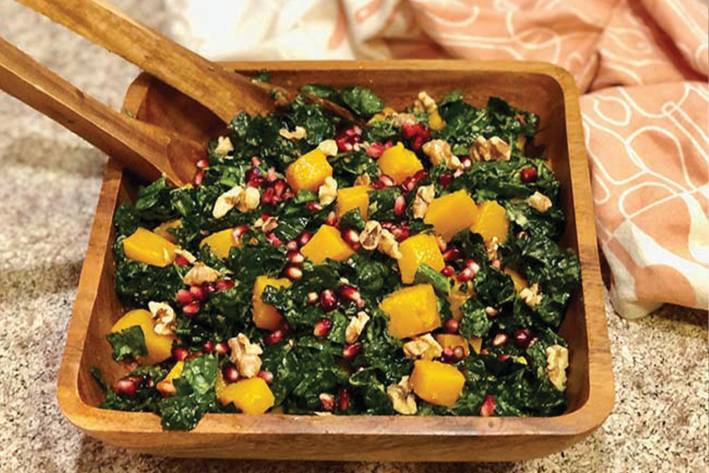 Kale, Butternut Squash, & Pomegranate Salad Kale, Butternut Squash, & Pomegranate Salad in a wooden salad bowl with wooden salad utensils.