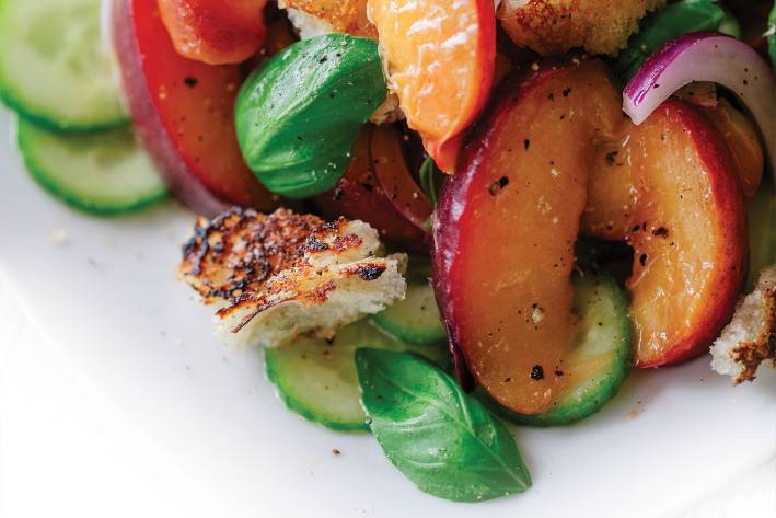 Peach Panzanella A close up image of Peach Panzanella on a white plate.