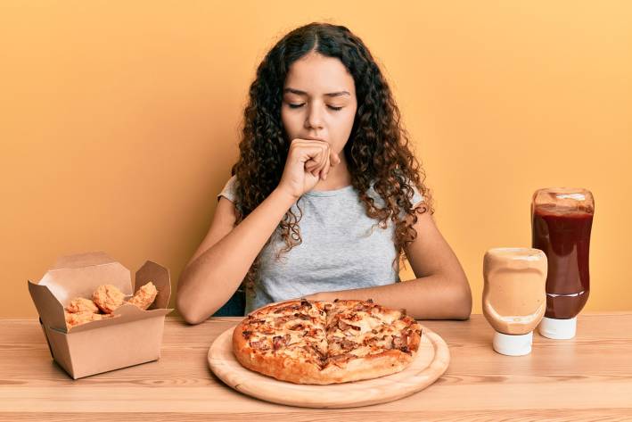 Junk Food Raises Asthma Risk a girl having trouble breathing while eating junk food