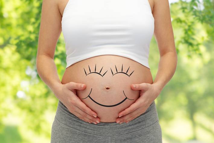 A Chemical-Free Pregnancy a pregnant woman with a smiley face drawn on her bump