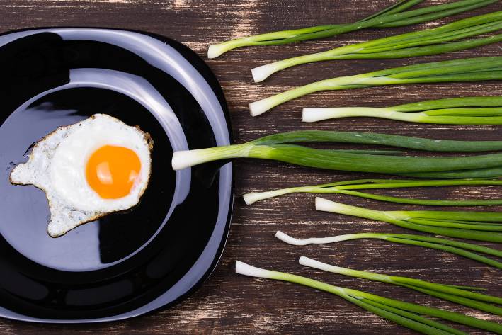Fertility Friendly Foods a fried egg and chives laid out to resemble an egg being fertilized