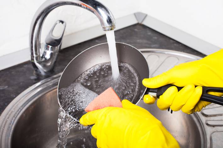 Taking Care of Pots and Pans Naturally scrubbing a frying pan under hot water