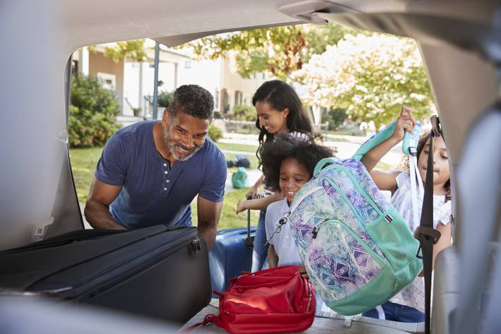 Vacation First Aid Kit a family packing the car for a vacation, including a red bag