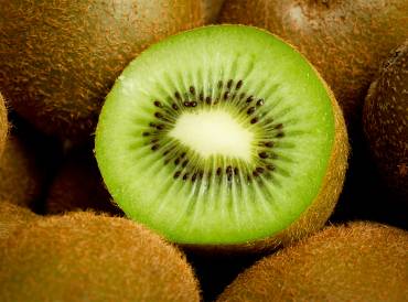 a sliced kiwi surrounded by whole kiwifruit
