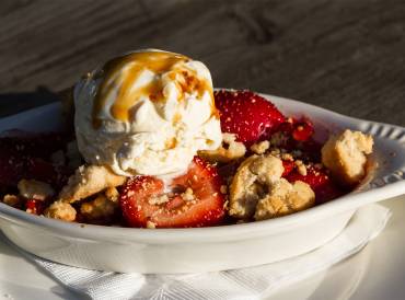a dish of strawberry-rhubarb crisp topped with ice cream